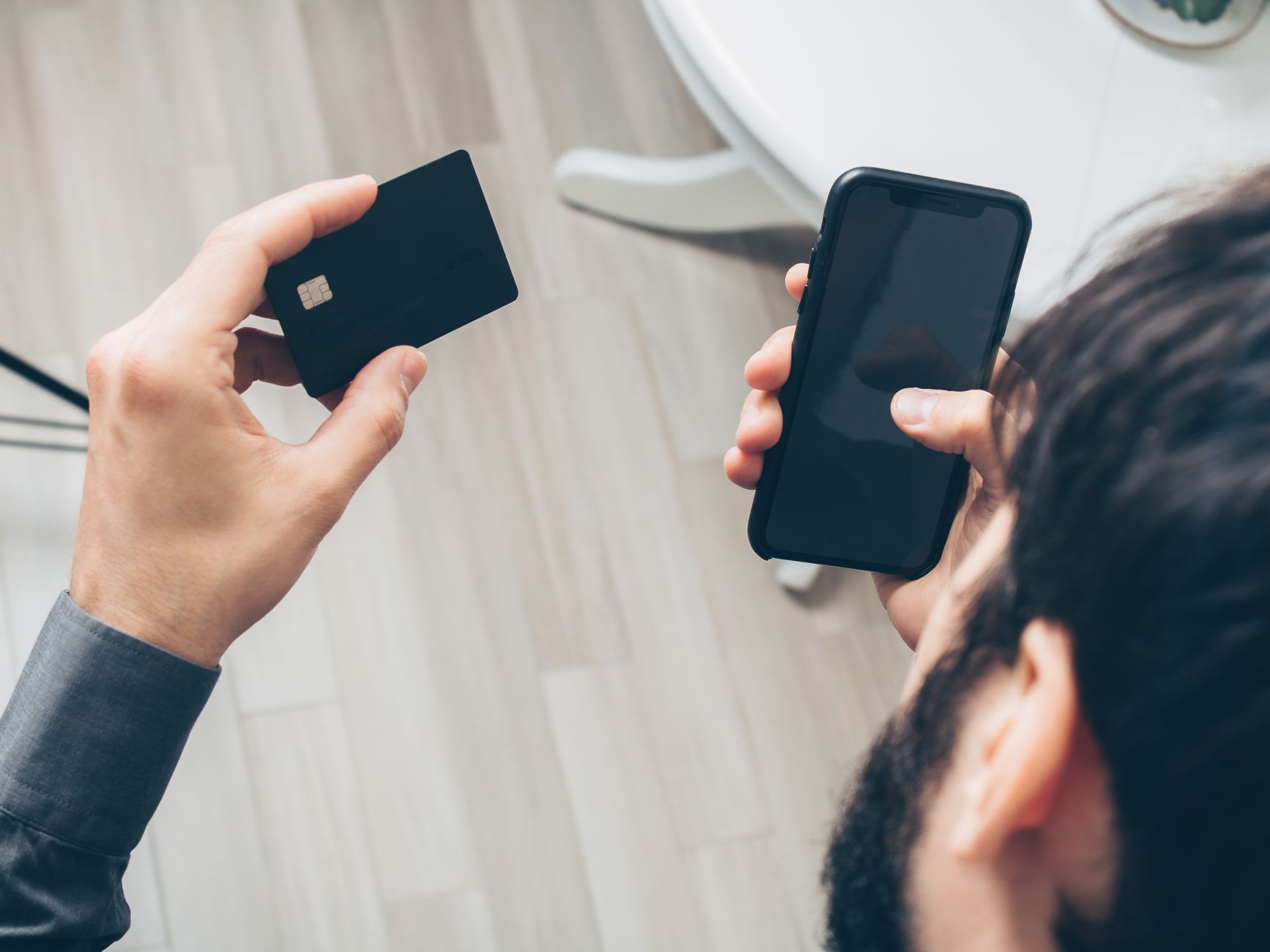 Mężczyzna trzyma smartfon i kartę płatniczą podczas płatności online